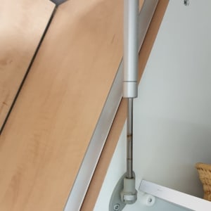 בוכנה מתכתית מחוברת לדלת עץ בארון