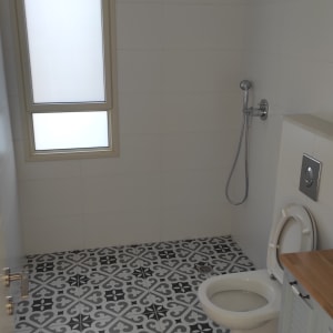 חדר אמבטיה עם מקלחת, אסלה ורצפה מעוצבת