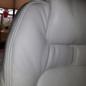 ריפוד עור לבן עם תפרים על משענת כיסא