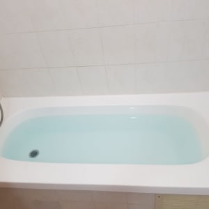 אמבטיה לבנה עם מים, ברז ומקלחת יד