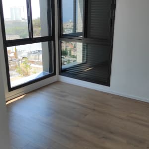 חדר ריק עם רצפת עץ נקייה וחלונות גדולים