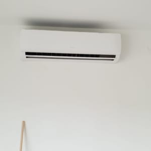 מזגן מותקן על קיר לבן עם אדם מתקין