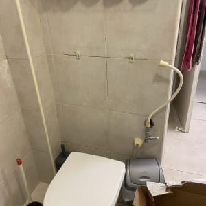 אסלה עם פומפה וצינור מים מחובר לקיר