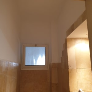 קיר עם אריחים בהתקנה, חלון קטן, תאורה עליונה