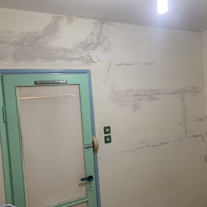 קיר עם תיקוני טיח סביב דלת ירוקה