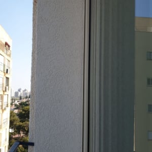 קיר חיצוני עם טיח מחוספס ליד חלון זכוכית