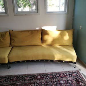 ספה צהובה עם כריות גדולות על רצפת אריחים