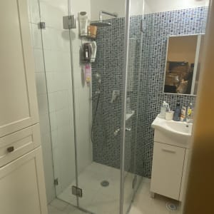 מקלחון זכוכית עם מדף מוצרים ומקלחת יד