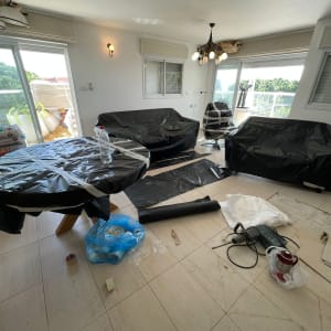 חדר עם רהיטים מכוסים, כלי עבודה ויריעות פלסטיק