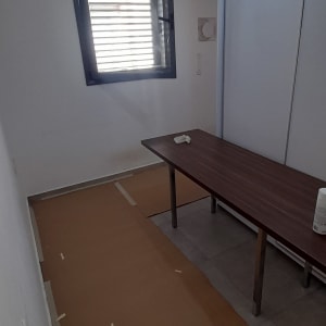 חדר עם שולחן, נייר חום על הרצפה, מנורה תלויה