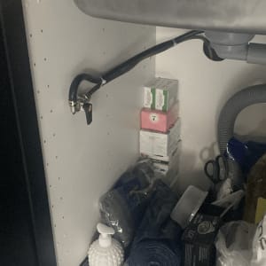 ארון מתחת לכיור עם צינור גז ומוצרים שונים