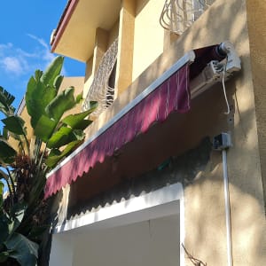 סוכך בד אדום מותקן על קיר חיצוני של בית