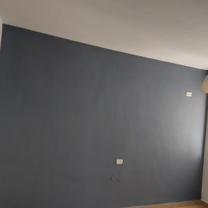 קיר צבוע בכחול כהה עם חלון בצד ימין