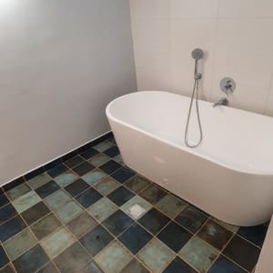 אמבטיה עם רצפת אריחים כהים וברז מקלחת