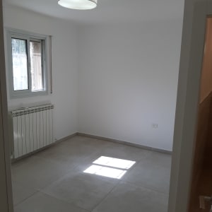 חדר ריק עם רצפת אריחים, חלון ותאורה עגולה