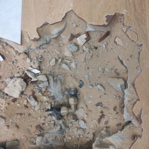 צינור מתכת חשוף עם חיבורים על רצפה שבורה