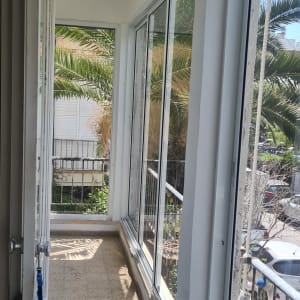 חלונות אלומיניום במרפסת סגורה עם נוף חיצוני