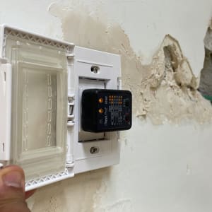 בודק חשמל מחובר לשקע בקיר