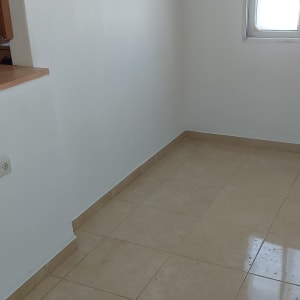 קיר לבן חלק עם חלון קטן בצד ימין