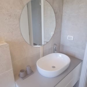 מראה עגולה תלויה על קיר בחדר אמבטיה