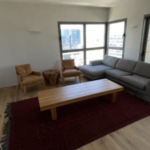 חדר עם ספה, כורסאות ושולחן עץ על שטיח אדום