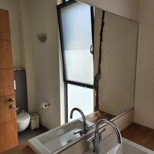 חלון זכוכית פתוח ליד מראה בחדר אמבטיה