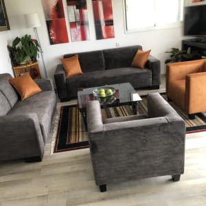 כריות כתומות על ספות אפורות בסלון מודרני