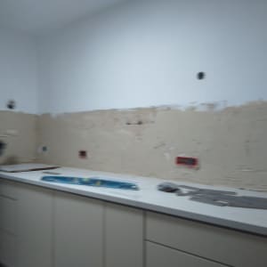 קיר מטבח בשיפוץ עם טיח וכלים על השיש