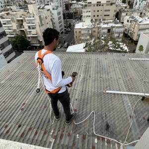 אדם עם רתמה על גג מתכת עם כלי עבודה