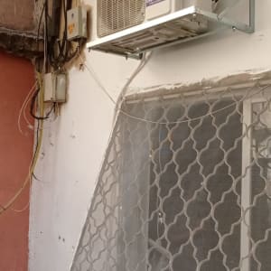 יחידת מזגן חיצונית מותקנת על קיר חיצוני עם חיווט חשמלי.