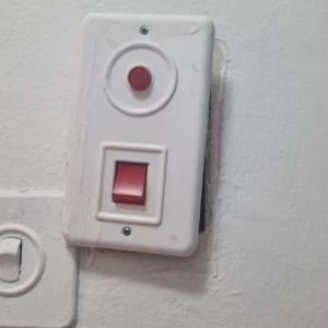מתג חשמלי עם כפתור אדום על קיר לבן