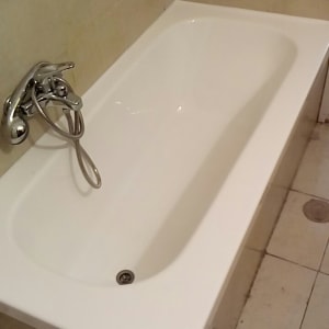 אמבטיה לבנה עם ברז כרום על קיר אריחים