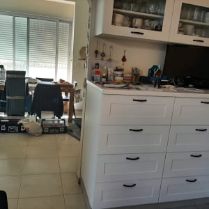 ארונות מטבח לבנים עם ידיות שחורות, כלים על השיש