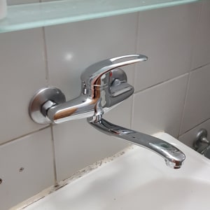 ברז כרום מותקן על קיר מעל כיור לבן