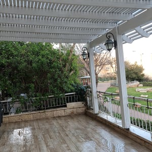 פרגולה לבנה מעץ עם רצפת דק רטובה