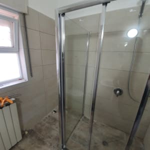 מקלחון חדש עם דלתות זכוכית ורצפה לא גמורה