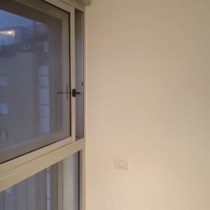 חלון זכוכית עם מסגרת מתכת וקיר לבן