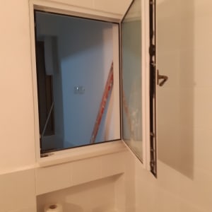 חלון אלומיניום פתוח עם מסגרת לבנה