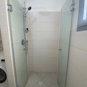 מקלחת עם דלתות זכוכית וראש גשם