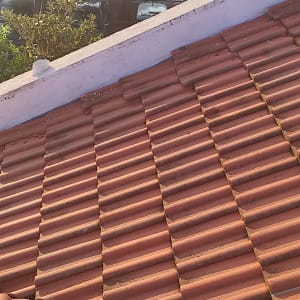 רעפים חומים על גג עם קיר לבן