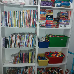 מדפים עם ספרים, משחקי קופסה וקופסאות צעצועים צבעוניות