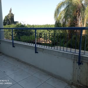 מעקה מתכת כחול על מרפסת מרוצפת