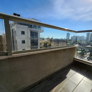 מעקה זכוכית במרפסת עם נוף עירוני