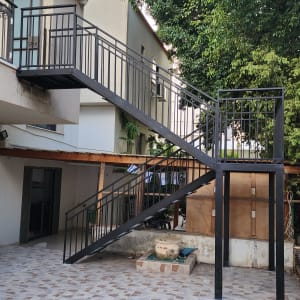 גרם מדרגות מתכת עם מעקה שחור בחצר