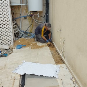 אדם עובד על צנרת מים ליד קיר חיצוני