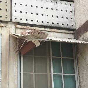 גג מתכת קטן עם עלים יבשים מעל חלון