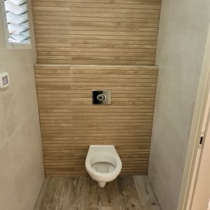 אסלה תלויה על קיר עם אריחים מעץ