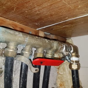 צינורות מתכת עם ברז אדום מתחת לכיור