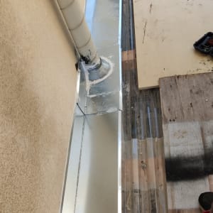 תעלת ניקוז מתכתית ליד קיר עם צינור פלסטיק