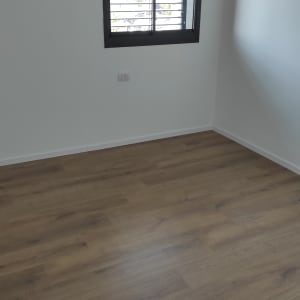 חדר ריק עם רצפת עץ נקייה וחלון